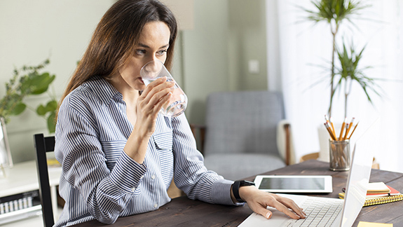 image-woman-drinking-water-using-laptop-continence-care-training-bladder-management